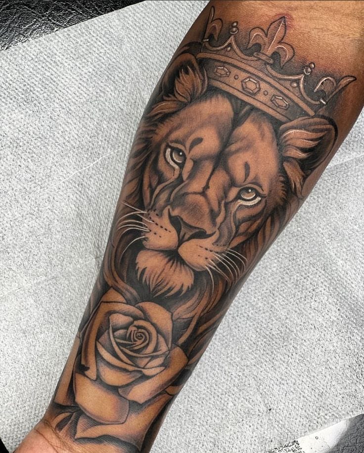 Crowned lion with rose tattoo on forearm